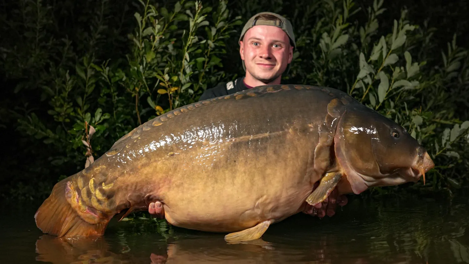 Angler mit riesigem Spiegelkarpfen