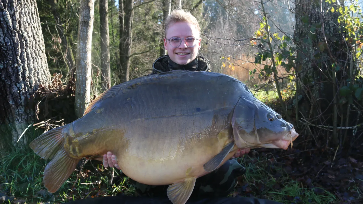 Angler mit riesigem Spiegelkarpfen